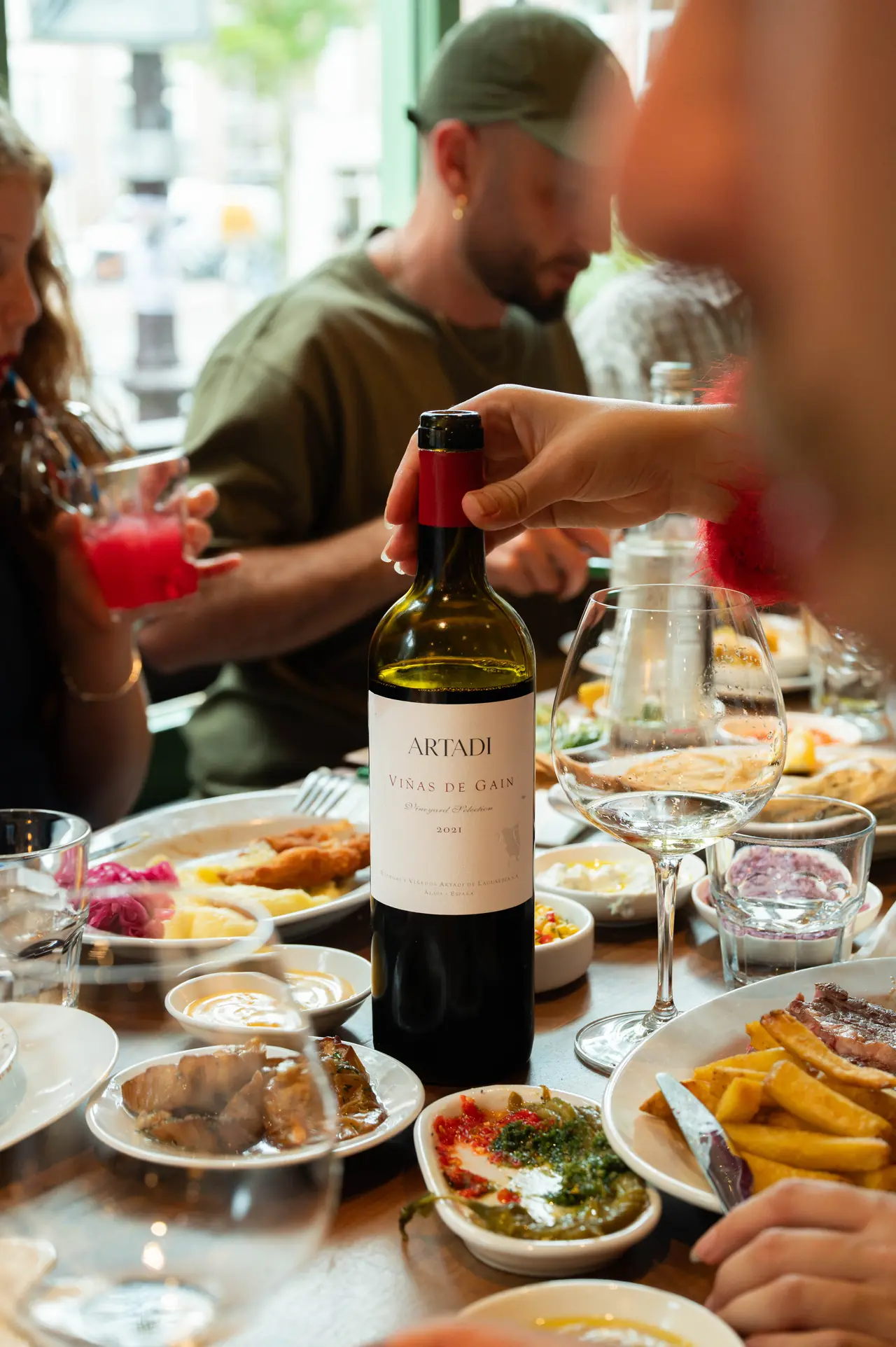 A bottle of Artadi Viñas de Gain on a table full of shared dishes