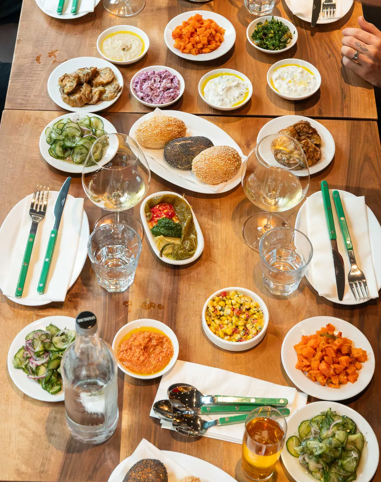 Bread buns and small salads and dips spread across the table